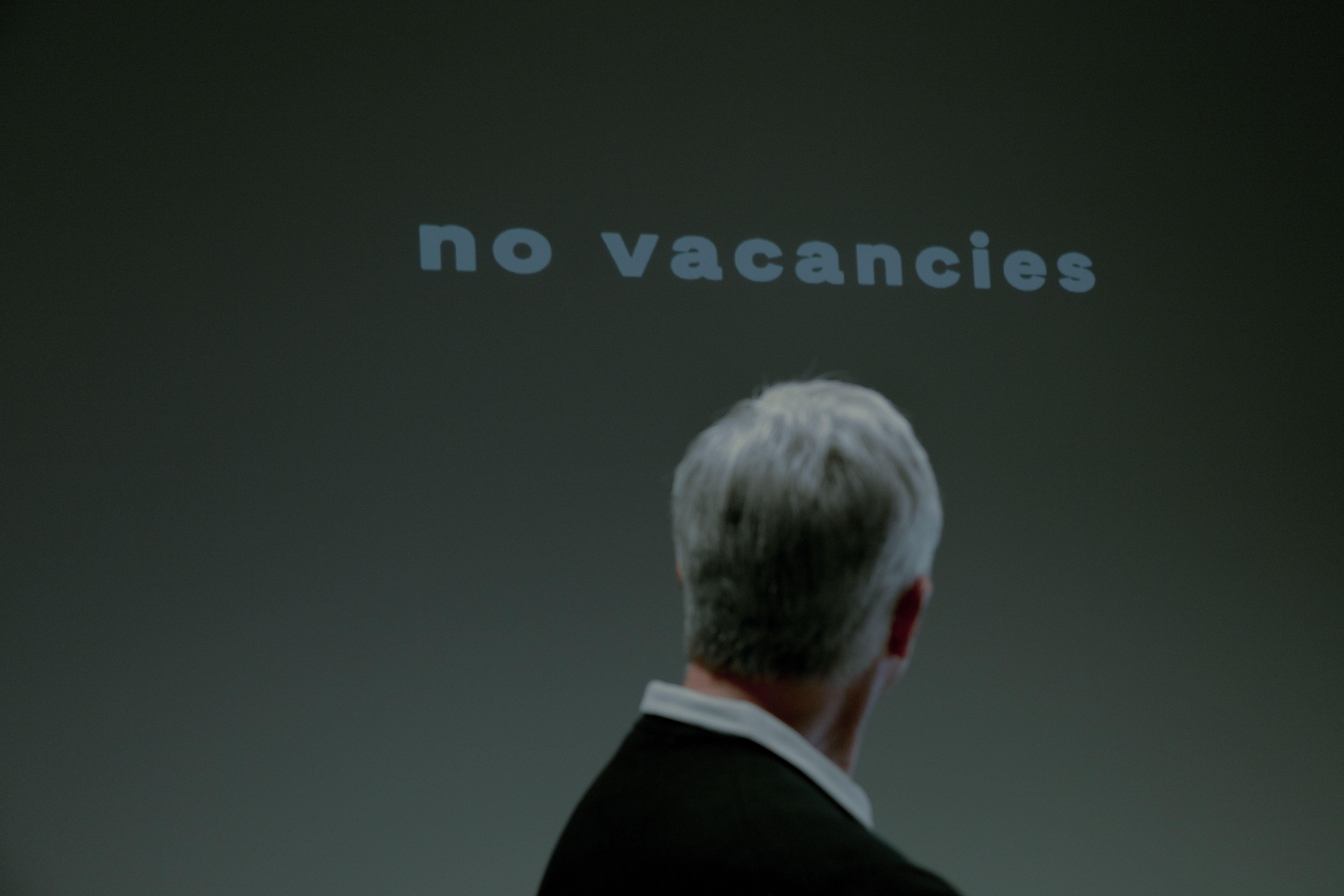 Persona observando un cartel de "no vacancies", representando la incertidumbre en la inversión de Bill Ackman
