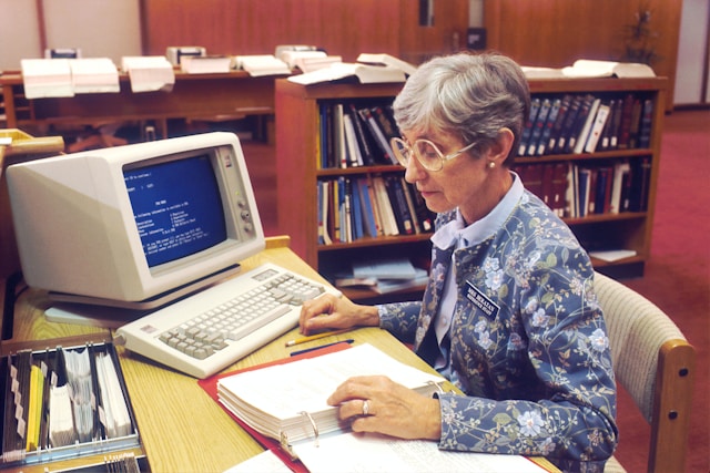 Empleado utilizando un ordenador acciones IBM en un entorno de oficina, representando la historia y evolución tecnológica de IBM.