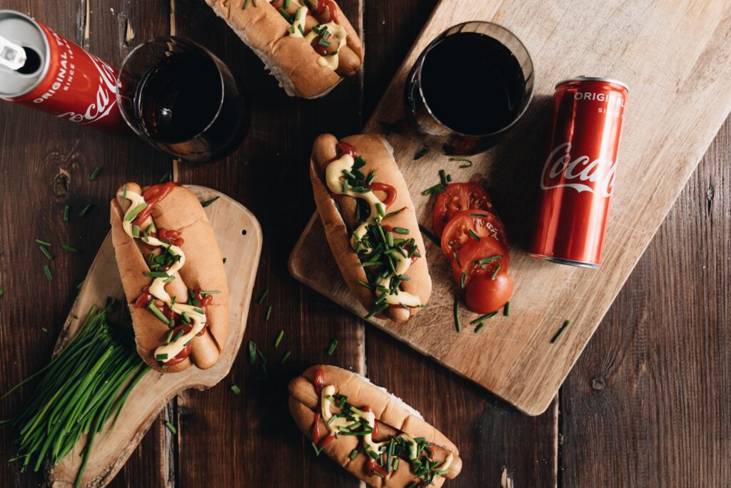 Lata de acciones Cocacola servida junto a una comida con perritos calientes.