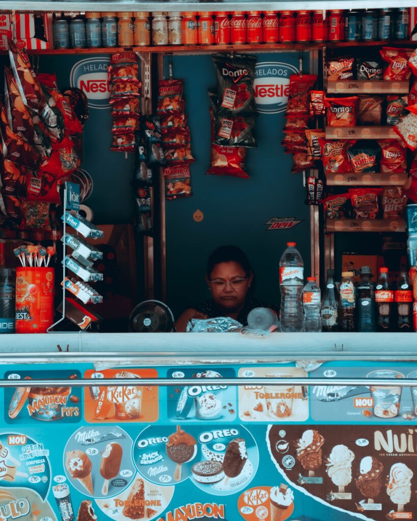 Puesto de alimentación con productos de acciones Nestle, helados y snacks expuestos para la venta.