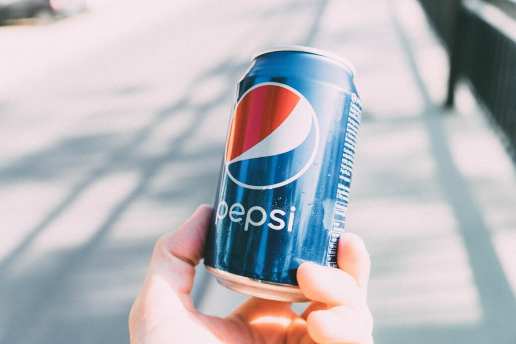 Lata de acciones Pepsico sostenida en la mano con el logotipo visible.