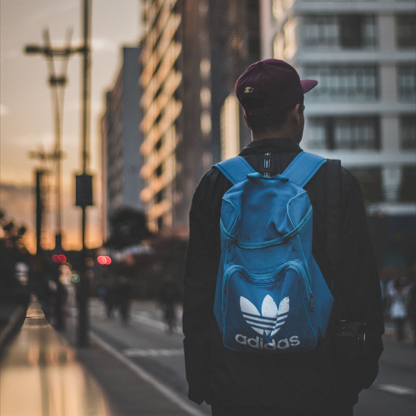 Persona caminando con una mochila acciones Adidas en un entorno urbano